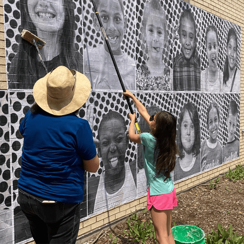 Wheat pasting student photos on the side of Kirkwood Elementary as part of an Inside Out Project action.