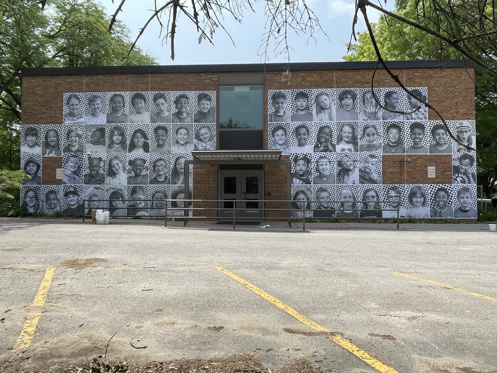 Current student faces wheat pasted on the side of Coralville Central Elementary School.