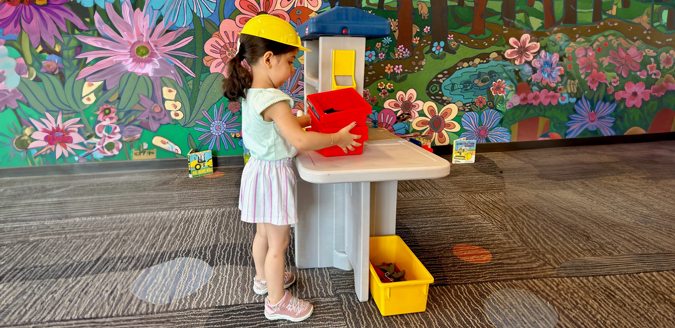 A girl playing at a toy workbench.