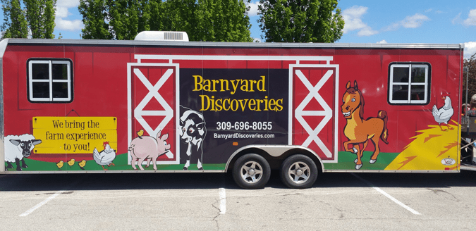 Barnyard Discoveries trailer with barn doors and farm animals painted on side.