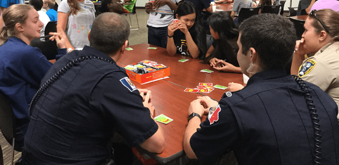 Coralville teens and police officers playing a game of Uno.