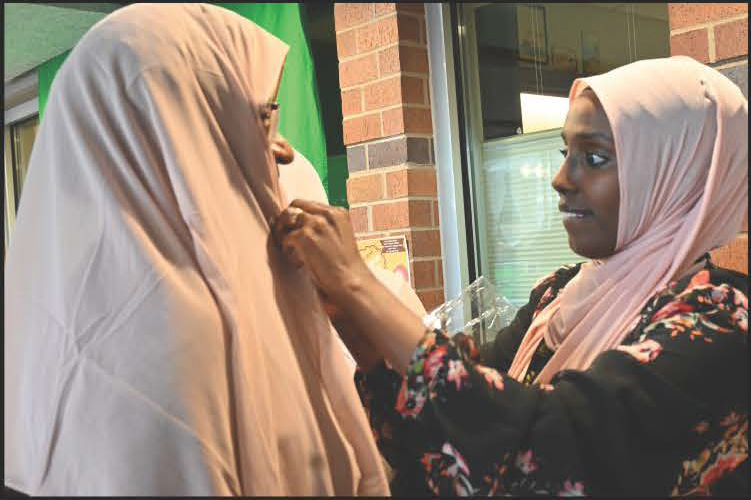 Community Resources Navigator helping a patron try on a hijab at World Hijab Day