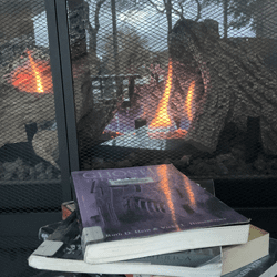 Books on ghost stories stacked in front of a fire place.