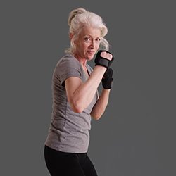 Athletic woman in her 50s posed in martial arts stance on gray backdrop