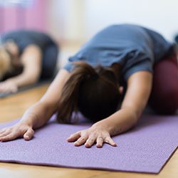 Women doing yoga training together and performing the child's pose on a mat, healthy lifestyle and fitness concept